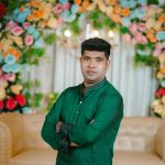 Elegant portrait of a man in traditional attire at a Bengali wedding, surrounded by colorful floral decor.