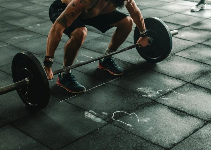A muscular man in a gym preparing to lift a heavy barbell, showcasing strength and fitness.