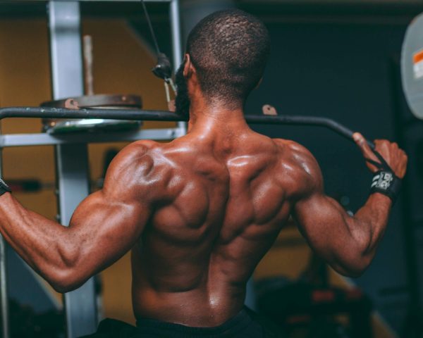 A muscular man performing lat pulldowns in a gym, showcasing strength and fitness.